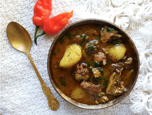 A full bowl contains paror mangxo with spoon and red chillis 