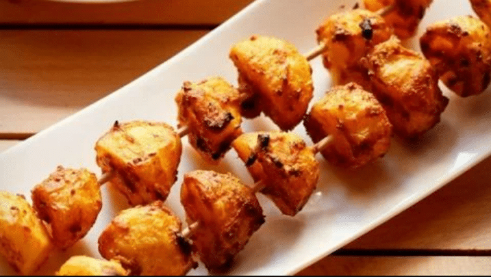 Plate of aloo tikka arranged on a wooden stick