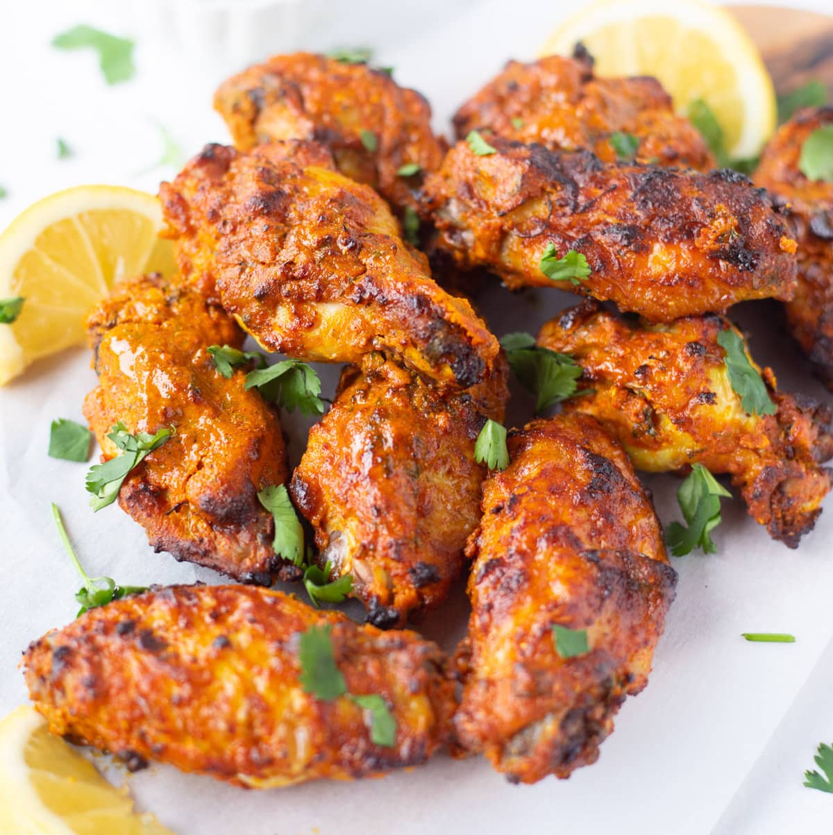 Tandoori chicken wings served with garnishings and lemon