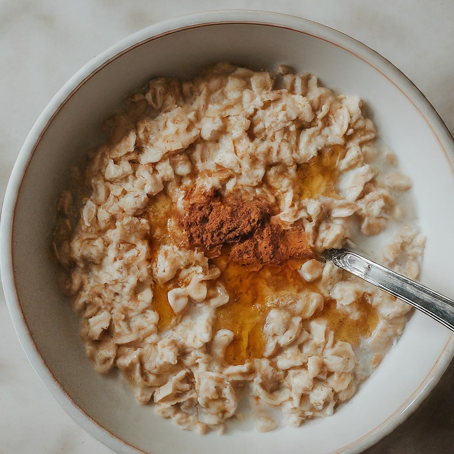 A bowl of rolled oats topped with milk, cinnamon, and honey