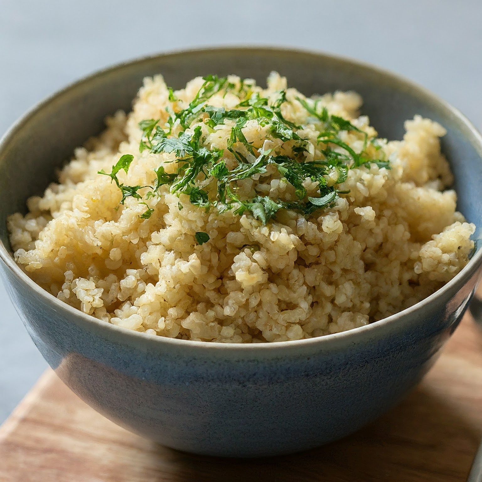 A bowl of cooked quinoa garnished with fresh herbs