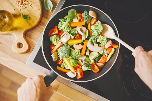 Colorful vegetables being saut ed in a black pan