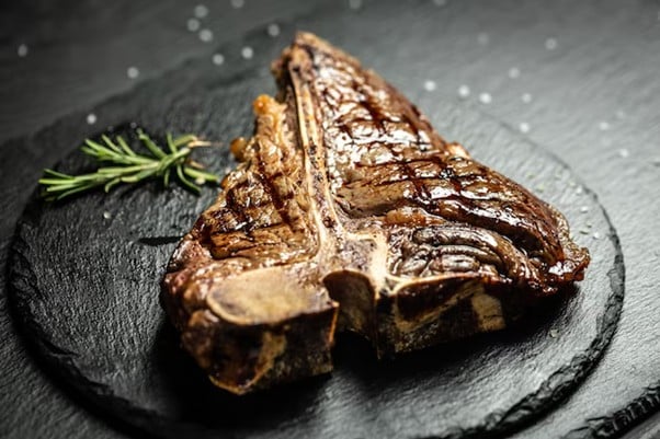 Grilled T bone steak on a black slate plate 