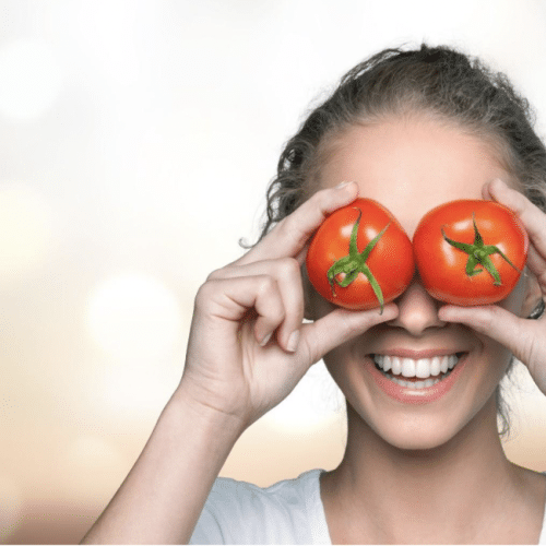 Girl laughing and holding two tomatoes