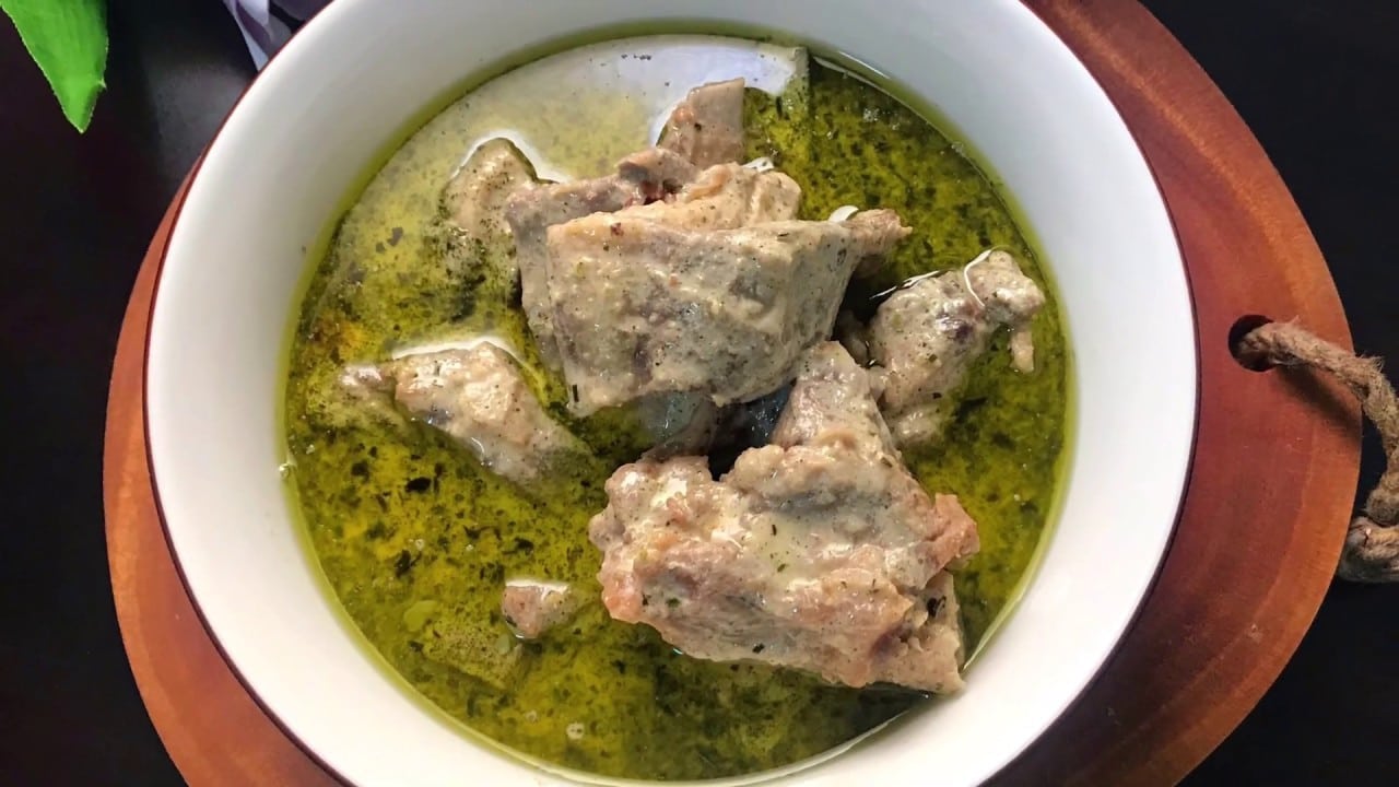 Pale green thick sauce coats large pieces of bone in meat in a white bowl