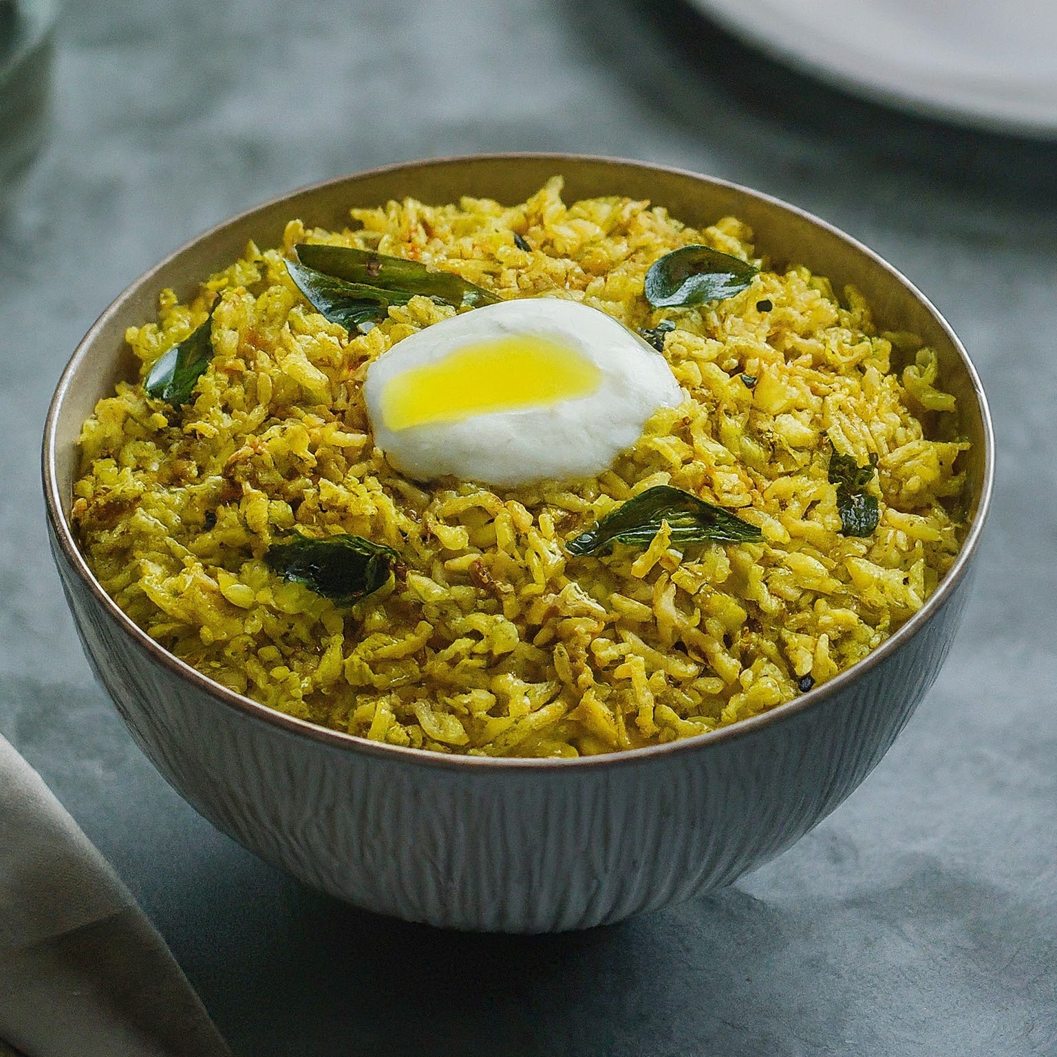 A steaming bowl of curry leaf rice, topped with a tangy yoghurt and a ghee drizzle.