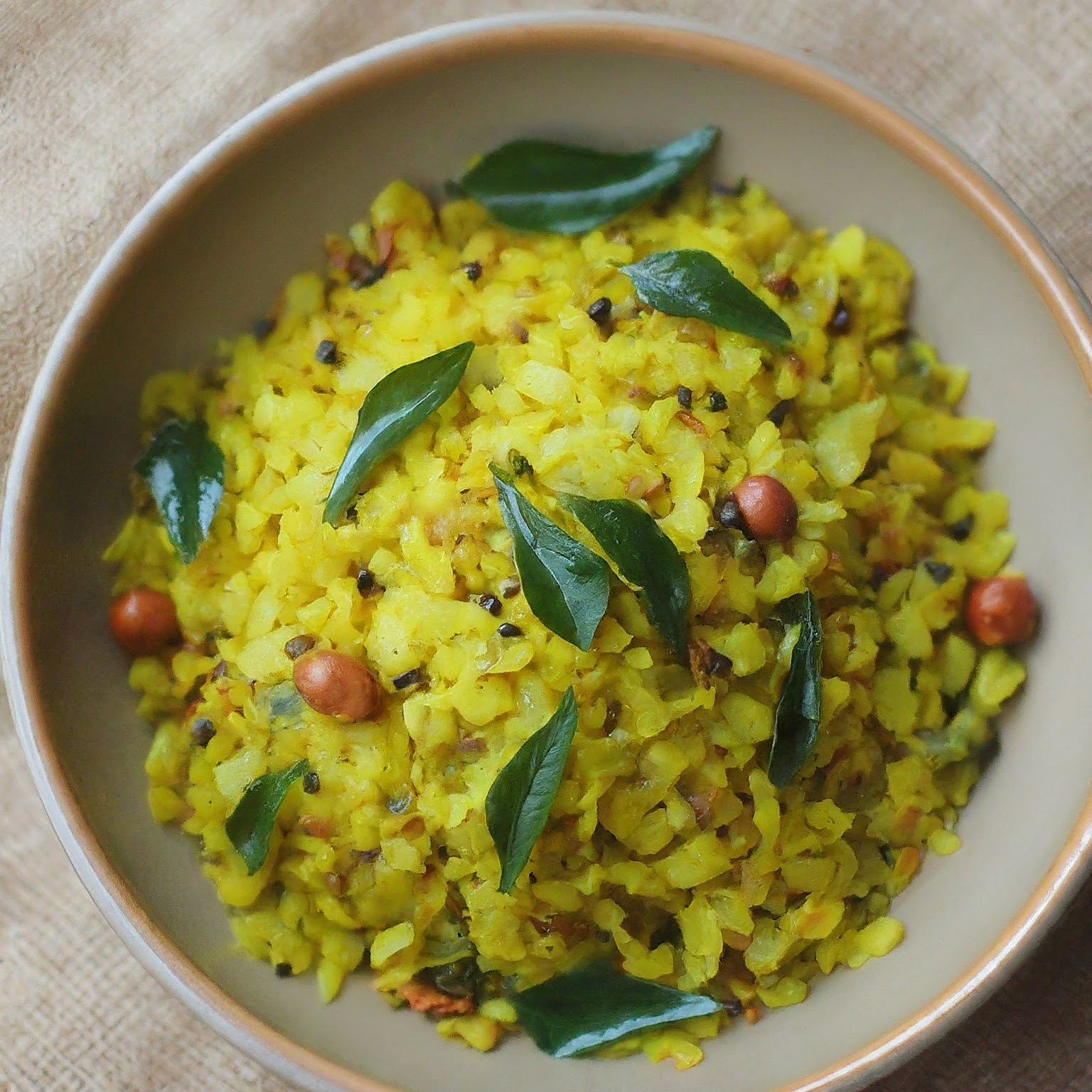 A close-up of a steaming bowl of curry leaf poha