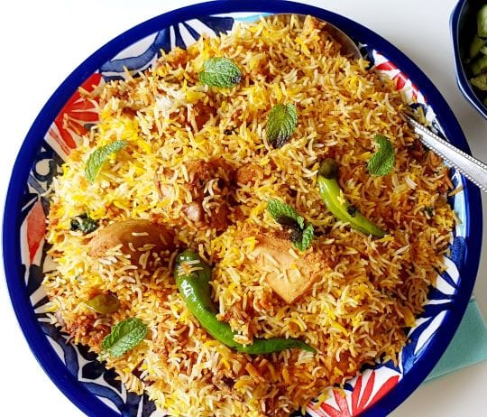 A plate full of Hyderabadi biryani added with green chilies and chicken