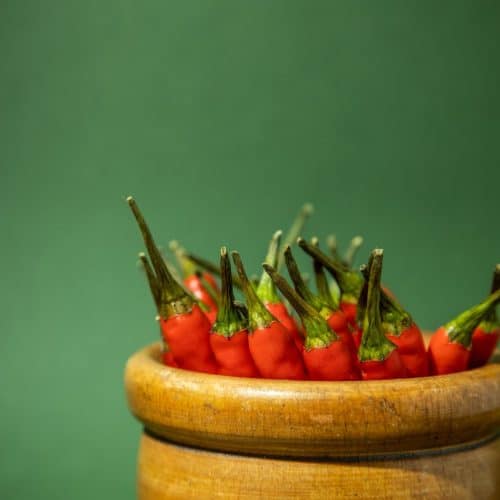 Small red chillies stacked in a wooden jar