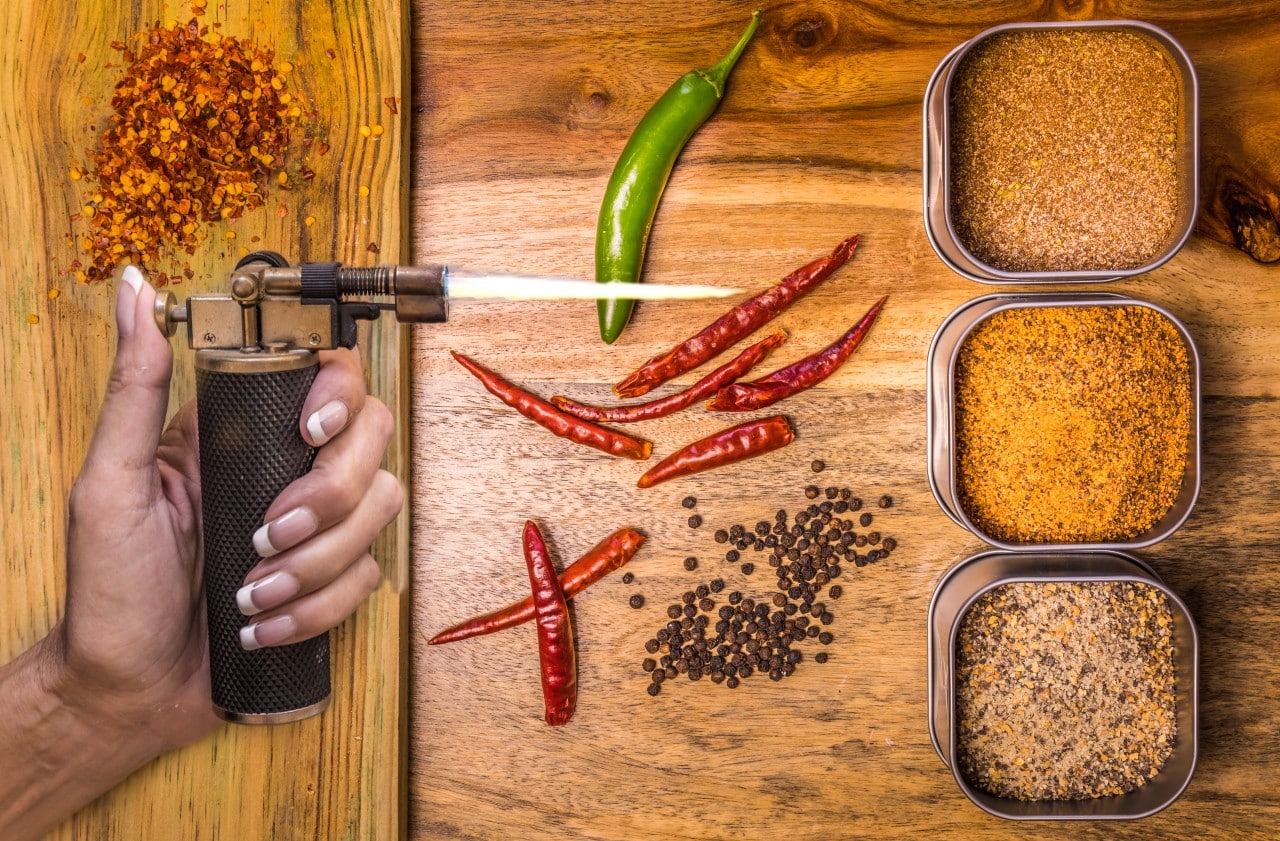 Chillies, spices, blowtorch on wooden background.