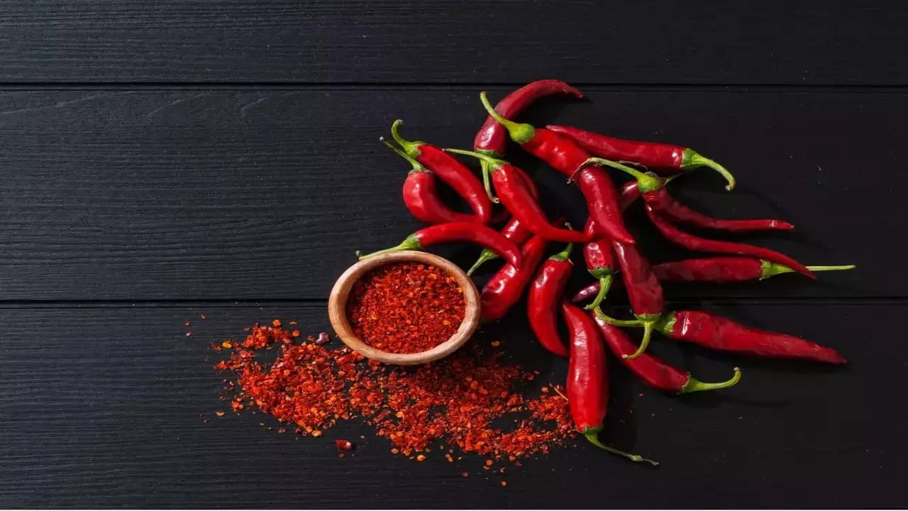 Red chillies and chilli powder on black background