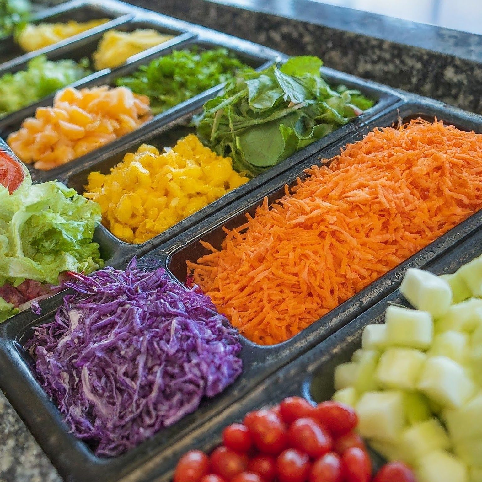 A colorful salad bar with a variety of fresh vegetables fruits and dressings 