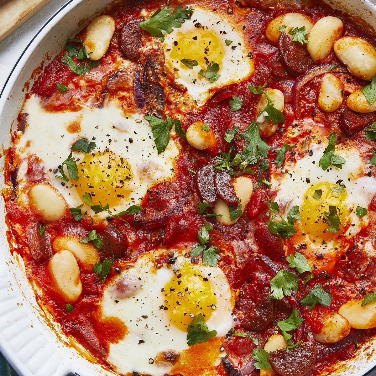 Baked Eggs with Chorizo and Butter beans dish in an oven proof skillet garnished with freshly chopped parsley