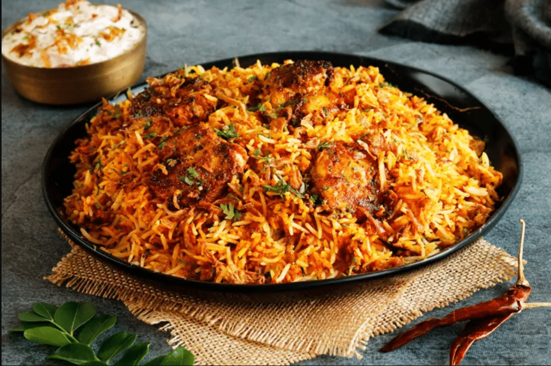 Luscious Hyderabadi biryani is nicely cooked with chicken and served in a black bowl.