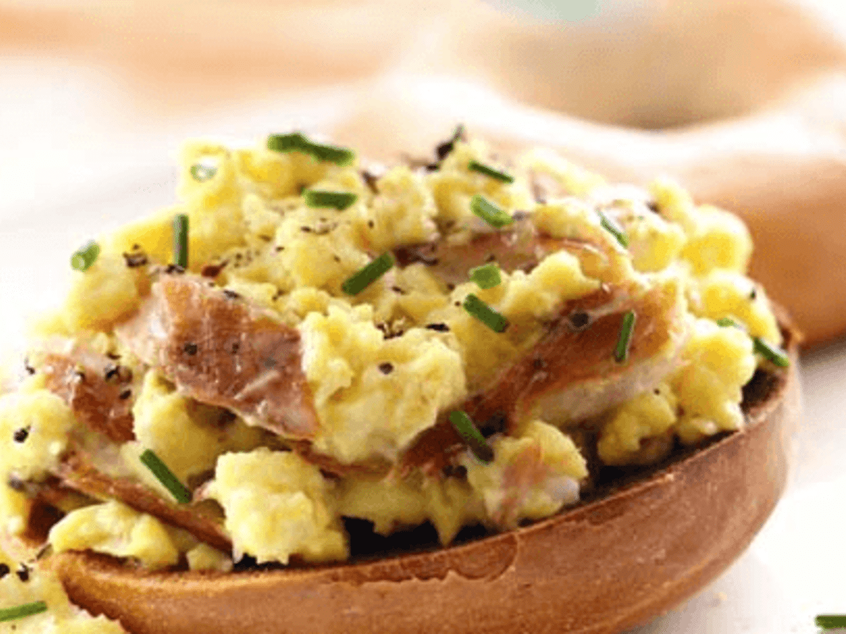 Smoked Mackerel Scrambled Eggs served on a plate garnished with fresh dill and sided with grilled tomatoes 