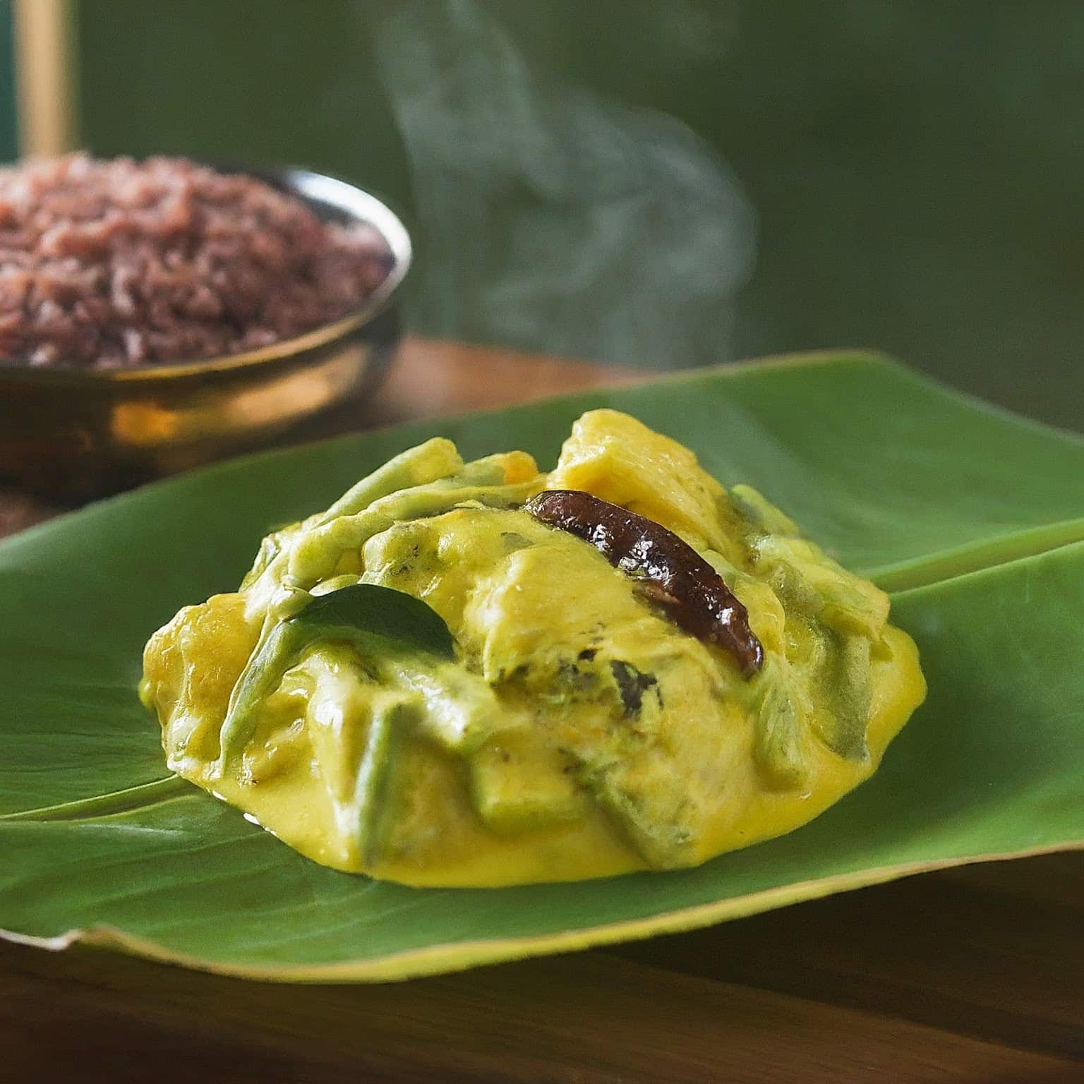 Avial with lead and red rice is in the background, served in a bowl, and is very hot.