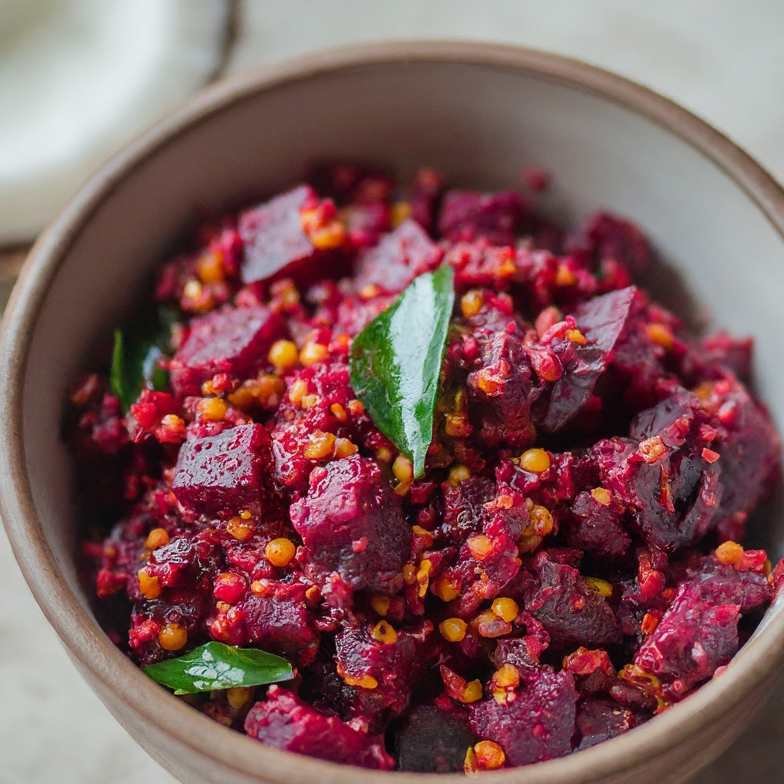 Dish of beetroot poriyal and coconut with a green leaf on top