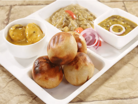 Baati chokha served in a white squared plate with dal and khichdi