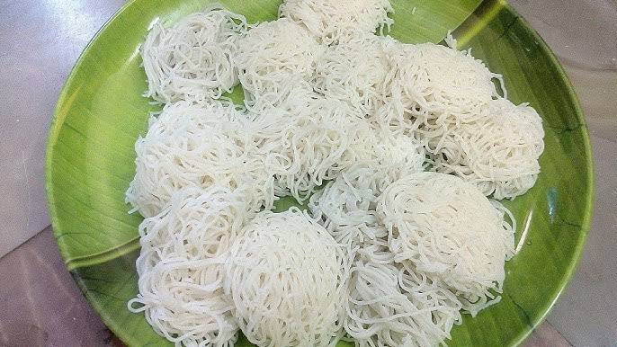 Freshly made noolputtu served in white plate with chicken curry