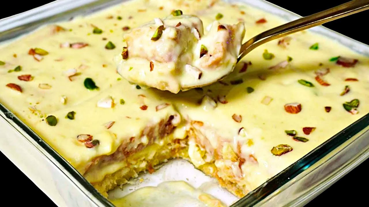 Spoonful of Shahi Tukda with a square tray filled with the sweet dish