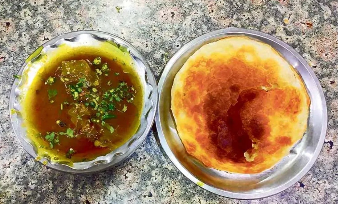 a bowl full of nihari is served with kulcha