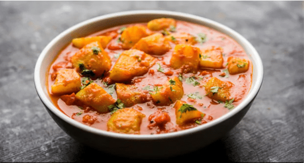 aloo badi rasedar served hot in a black coloured bowl