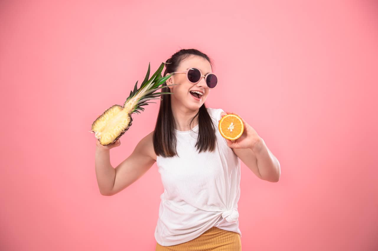 Woman holding a sliced pineapple and orange